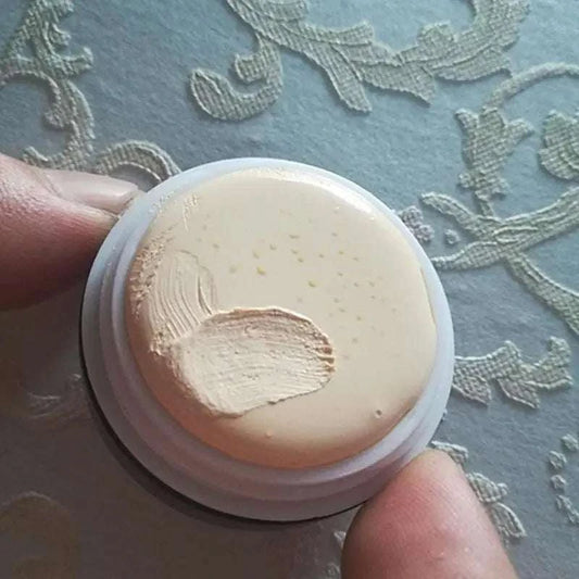 Freckle removal pearl cream in a small container, showing creamy texture.