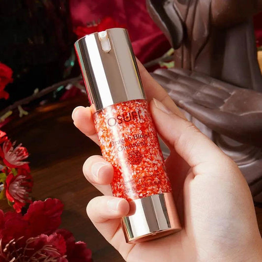 Moisturizing face cream in a red and silver bottle held in hand.